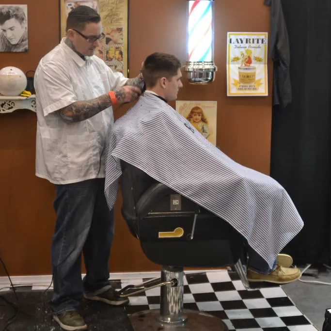 Barbero atendiendo a un cliente en el local
